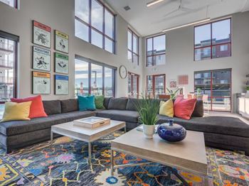 A living room with a grey couch, a coffee table, and a colorful rug.